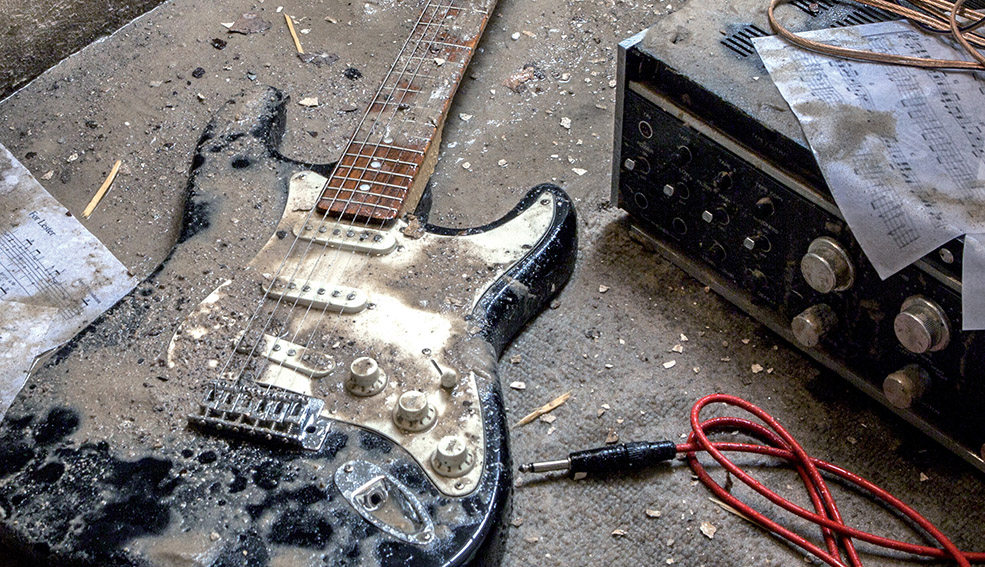 dreckiger Kellerboden mit nasser Gitarre und Verstärker