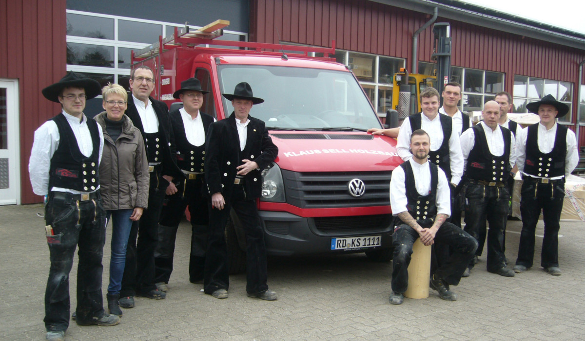 Team mit Auto vor Firma
