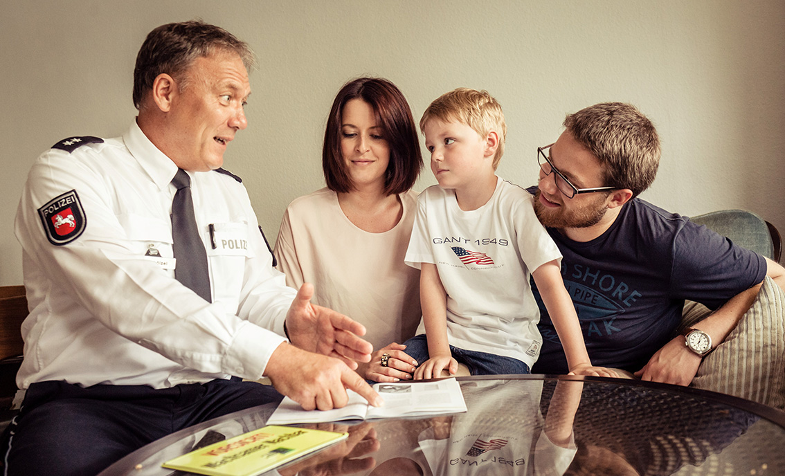 Polizist erklärt kleinem Jungen und Eltern etwas